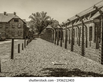 Oświęcim, Poland - June 05, 2019: Electric fence with barbed wire and brick prison buildings at the Auschwitz-Birkenau concentration camp in Oświęcim, Poland. Europe. Oswiecim