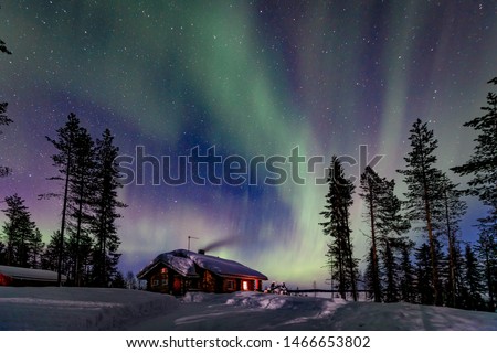 Polar arctic Northern lights Aurora Borealis activity over wooden cabin in winter Finland, Lapland