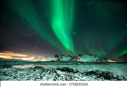 polar lights also called northern lights or aurora borealis in northern norway during winter above a fjord and snow covered mountains - Shutterstock ID 1718231524