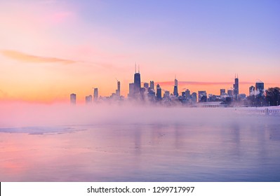 The polar vortex storms over the Chicago skyline. Mist carries off a frozen Lake Michigan during a colorful sunrise.