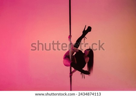 Pole dance performance by sexy young female in studio.