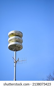 Pole with Dutch acoustic air alarm system also known as air raid siren alert and also known as luchtalarm in Dutch with clear blue sky in Holland used to warn public for example during war or attack