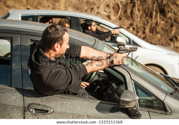 Police agent and bodyguard training action gun\
shooting from car. Special agent team weapons training and course\
on outdoor shooting\
range
