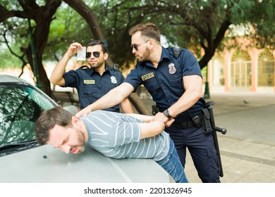 Police agents on duty arresting a criminal suspect making a drug deal in the streets 