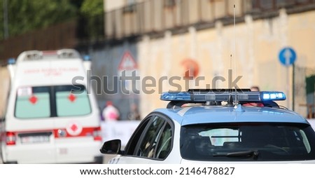 police car with blue flashing lights on it while escorting an ambulance to go to the hospital after the accident