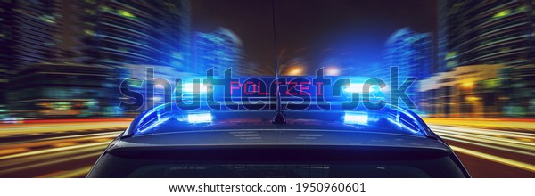 Police car with\
blue lights at night in a\
city