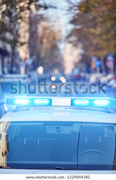 Police car with blue lights on the crime\
scene in traffic / urban\
environment.