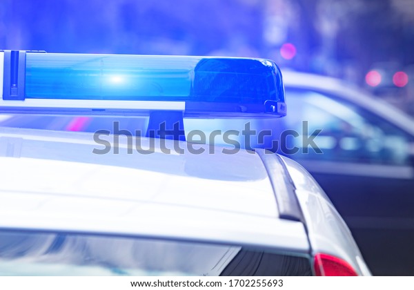 Police car with blue lights on the crime\
scene in traffic / urban\
environment.