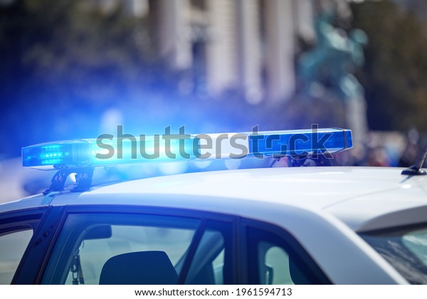 Police car with blue lights on the crime\
scene in traffic urban\
environment.