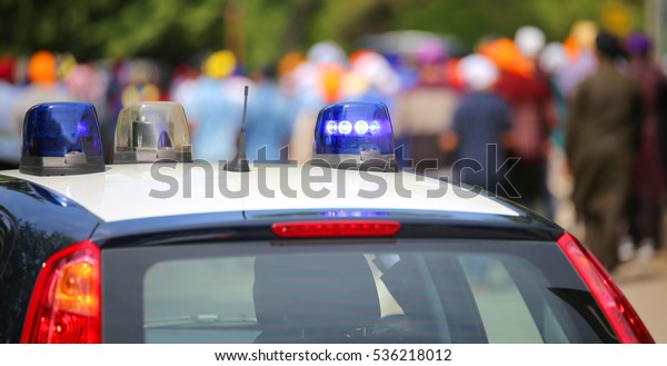 police car with blue sirens during the riot with a\
lot of people