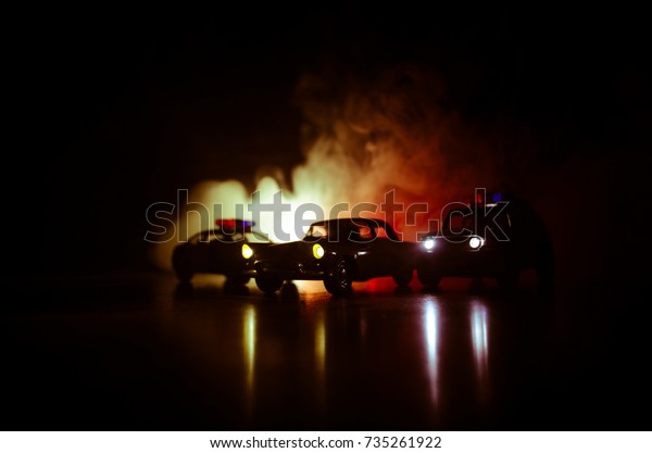 Police car chasing a car at night with fog\
background. 911 Emergency response police car speeding to scene of\
crime. Selective focus
