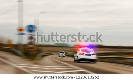 Police car chasing the offender on the road with flashing lights.