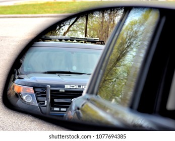 A Police Car Has A Motorist Stopped. The Drivers View In The Rear View Mirror