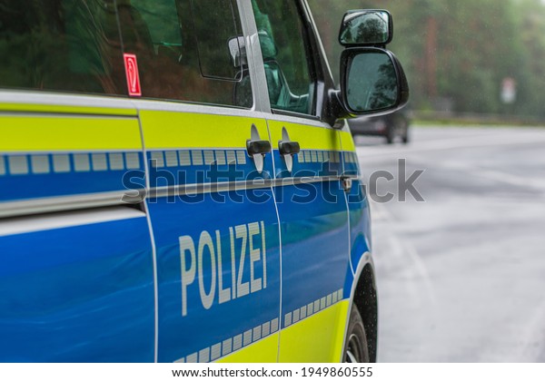 Police car from the side. Passenger side with doors and\
lettering Police on the body. Mirror window body from the passenger\
side with yellow and blue paintwork. Emergency bay with asphalt\
road. 