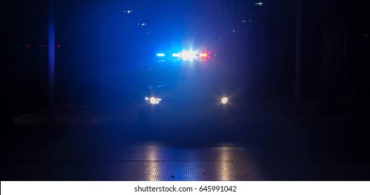 Police car with their lights on flashing red and blue at night.