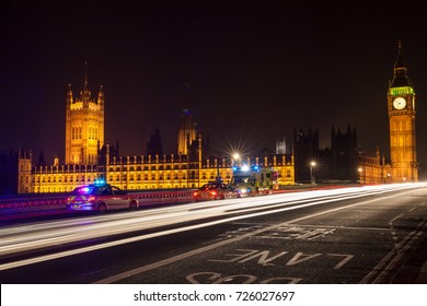 Police Cars And Ambulance On Westminster Bridge, London At Night With The Houses Of Parliament And Big Ben