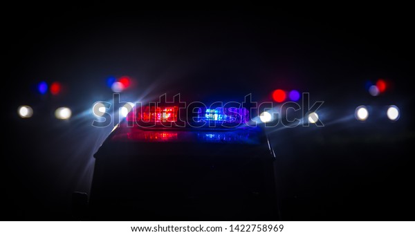 Police cars at night. Police car\
chasing a car at night with fog background. 911 Emergency response\
police car speeding to scene of crime. Selective\
focus