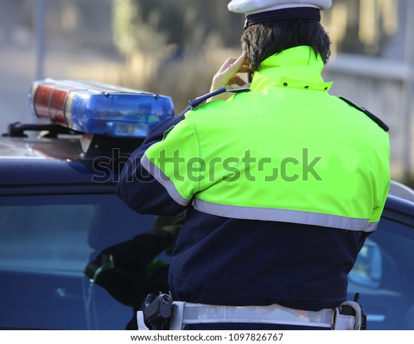 Police cars and policemen\
with a phosphorescent uniform use their cell phones during an\
emergency call