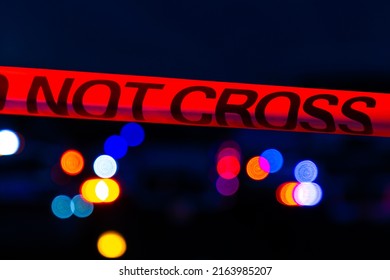 Police Crime Scene Tape In Front Of Flashing Lights At Night