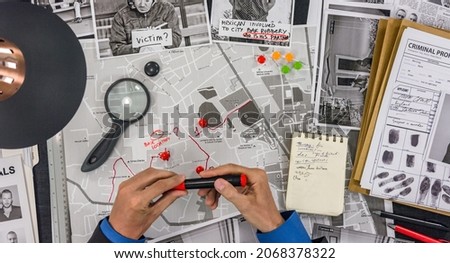The police detective draws a track on the map of the city and places a tag.
