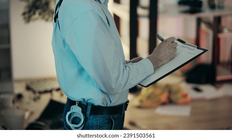 A police detective is filling out report papers while examining the crime scene in an apartment