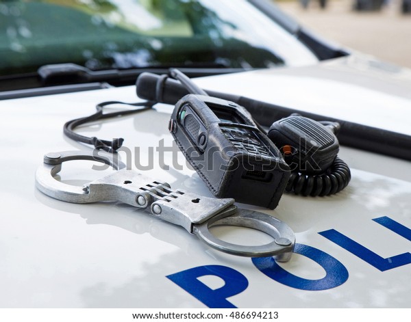 Police equipment on a  police\
car.  Handcuffs, baton and pager on top of a police car. Selective\
focus