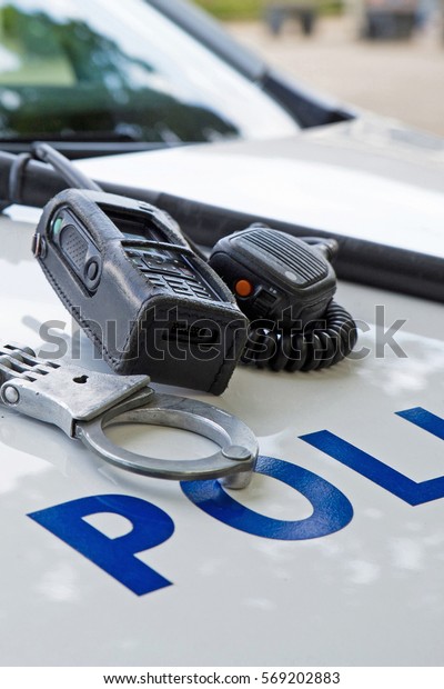 Police equipment on a  police\
car.  Handcuffs, baton and pager on top of a police car. Selective\
focus