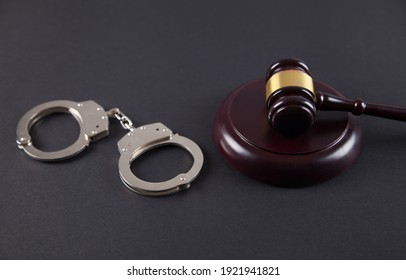 Police handcuffs and judge gavel on an isolated black background.