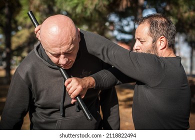 Police instructor demonstrates fighting, apprehension and arrest techniques using a police baton, outdoor in public park. Rubber baton, truncheon or nightstick
