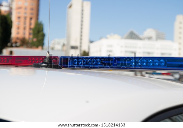 Police lights. Blue and red\
sirens on the roof of police car while policemen patrol the\
city