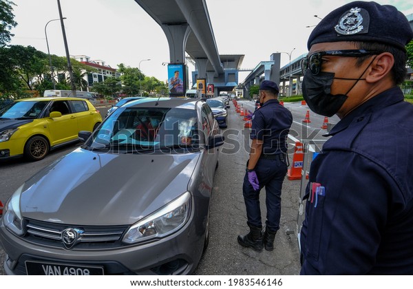 A police officer checks the\
documents of a passenger, both wearing protective masks, on a car\
at a checkpoint in Kuala Lumpur, Malaysia on June 1,\
2021.