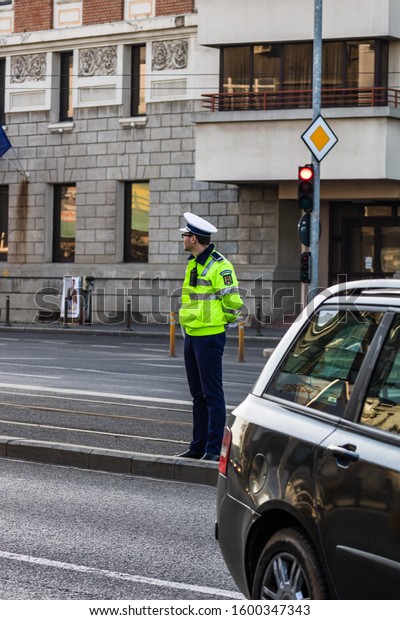 Police officer directing traffic in\
downtown junction in Bucharest, Romania,\
2019.