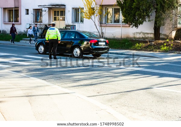Police officer directing\
traffic in downtown junction in Targoviste city. Targoviste,\
Romania, 2020