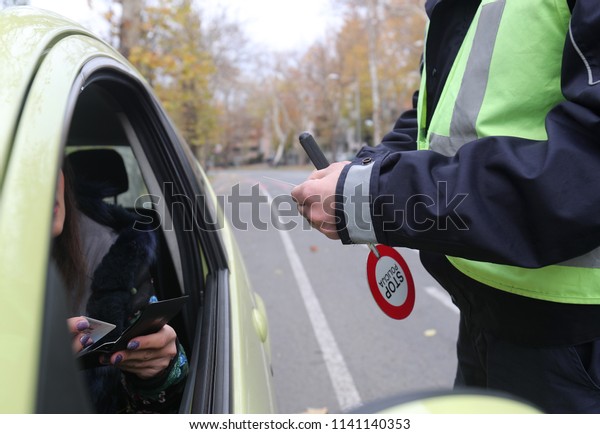 Police officer is doing a traffic check and\
looks at the documents.