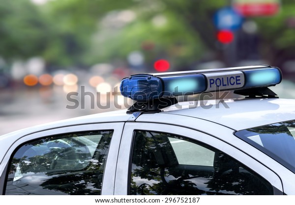 Police officer emergency service car driving\
street with siren light blinking\
