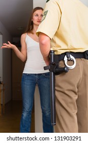 Police Officer At Front Door Of Home Interrogating A Woman Or Witness Regarding A Police Investigation