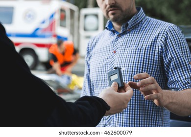 Police Officer Giving The Breathalyser To The Other Man