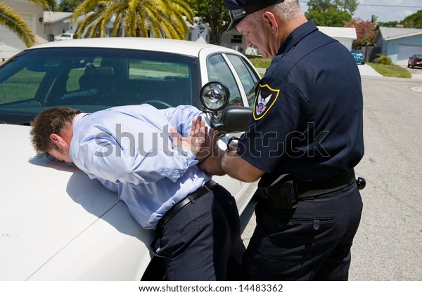 Police officer handcuffing and arresting a well\
dressed, white collar\
suspect.