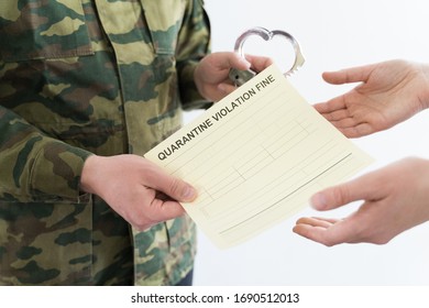 Police officer with handcuffs in khaki colored uniform stops people on the street for violating rules of quarantine of home self-isolation due to coronovirus covid-19 flu pandemic.Yellow fine receipt.
