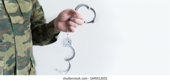 Police officer with handcuffs in khaki colored uniform stops and arrest criminal on the street for violating rules of quarantine of home self-isolation due to coronovirus covid-19. Flu world pandemic.