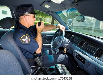 Police Officer In His Squad Car, Talking On His Radio.