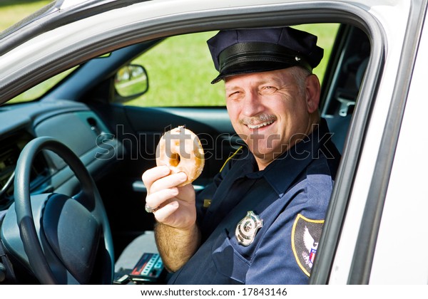 Police
officer in his squad car holding a
doughnut.