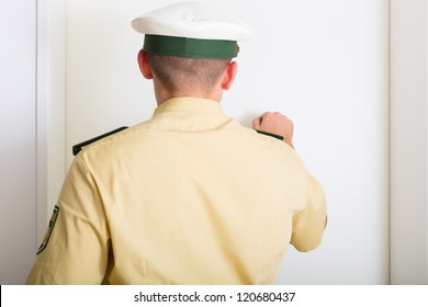 Police Officer Knocking On Front Door Of Home