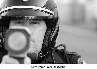 A Police Officer Pointing His Radar Gun At Speeding Traffic.