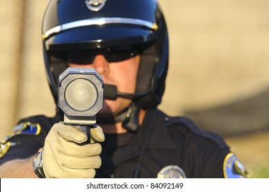 A Police Officer Pointing His Radar Gun At Speeding Traffic.