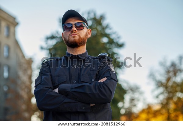 Police officer\
poses in uniform and\
sunglasses