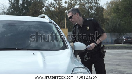 Police officer stopping the driver of a vehicle and questioning him over an alleged offence through the open window of the car