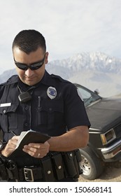 Police officer taking notes in front of car
