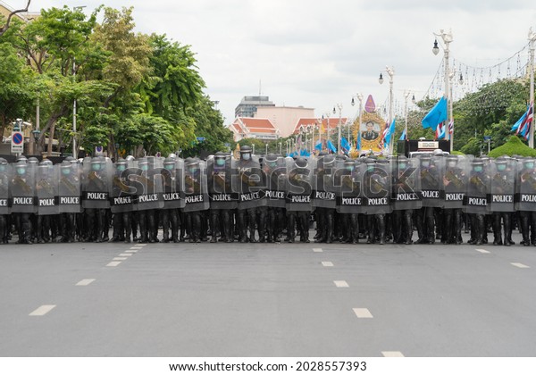 Police officer team with weapons and riot\
shield protection. Violence Against Demonstrators and protesters\
during COVID-19 pandemic. Riot in Bangkok, Thailand. Demonstration\
people. Cop authority.