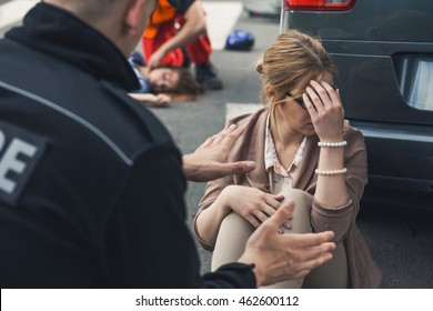 Police Officer Trying To Calm Down The Woman Sitting On The Ground